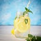 Coctail jar of lemonade and mint leaves on wooden table blue background