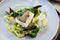 Cod fillet with cauliflower cream, asparagus, clam-wine sauce and mussles. Delicious seafood fish closeup served on a