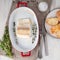 cod fish fillet, freshly cooked in oven with thyme in a porcelain dish for baking, bread on a plate, salt and pepper, white