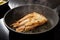 Cod fish fillet sautÃ©ed with thyme in a steaming frying pan on the black stove, copy space