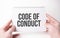 Code of Conduct word inscription on white card paper sheet in hands of a man. Black letters on white paper. Business concept