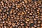 Coffee beans on a black table fill the whole space, wallpaper or background