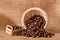 Coffee beans and cinnamon on a background of burlap. Roasted coffee beans background close up. Coffee beans pile from top with