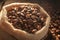 Coffee beans close up Burlap bag on wooden background, rich aroma