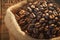 Coffee beans close up Burlap bag on wooden background, rich aroma