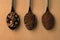 Coffee beans, coarse coffee, finely ground coffee in black spoons close-up