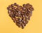 Coffee beans and dried oranges on a yellow background. Heart made of coffee beans. Love for coffee.