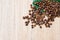 Coffee beans on a green leaf and scattered on a light wooden table, top view, closeup grains, flat lay, place to insert text, copy