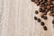 Coffee beans on a light wooden table, top view, closeup grains, flat lay, place to insert text, copy space