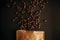 Coffee beans scattered from paper pack on black background Flat lay. Fresh aromatic roasted coffee beans top view. Coffee shop