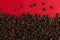 Coffee beans are scattered on a red paper background close-up, commercial copy space