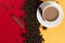 Coffee beans are scattered on a red and yellow paper background and a white cup, cinnamon, star anise, concept, commercial copy