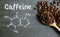 Coffee beans with spoon and chemical structure of caffeine on a wooden table