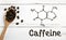 Coffee beans with spoon and chemical structure of caffeine on a wooden table