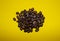 coffee beans sprinkled on a yellow background, top view