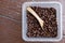 Coffee beans, square shaped box with wooden spoon. Wooden surface.