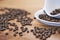 Coffee beans in a white cup on a wooden table with a modern coffeeshop in the background and beas selective focus.