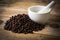 Coffee beans on wooden background and white mortar