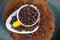 Coffee beans in a yellow cup on white ceramic tray on a stump