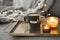 Coffee in black mug served on a metal tray with burning aroma candles, christmas lights as background