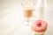 Coffee break: cappuccino and fresh sugary pink donut/Coffee break: cappuccino and fresh sugary pink donut on a white marble