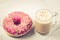 Coffee break: cappuccino glass with fresh sugary pink donut/Coffee break: cappuccino glass with fresh sugary pink donut over white