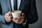 Coffee break, close-up of a businessman\\\'s hands in a suit holding a cup of delicious coffee