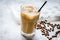 Coffee break with cold iced latte and beans on stone table background