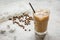 Coffee break with cold iced latte and beans on stone table background