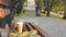 Coffee break on empty bench in autumn city park, woman with baby carriage at public park walkway on background