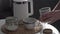 Coffee break, woman makes coffee pour instant grains and sugar into cup and pours boiling water in kitchen early in