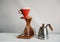 Coffee brewing in red purover on wooden coffee station. Glass serving jug. Kettle gooseneck. White background