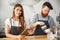 Coffee Business Concept - Cheerful baristas looking at their tablets for online orders in modern coffee shop.