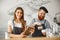 Coffee Business Concept - Cheerful baristas looking at their tablets for online orders in modern coffee shop.