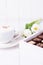 Coffee cappuccino with ceylon cinnamon, luxury chocolates candy and white tulips on a white background