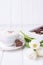 Coffee cappuccino with ceylon cinnamon, luxury chocolates candy and white tulips on a white background