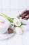 Coffee cappuccino with ceylon cinnamon, luxury chocolates candy and white tulips on a white background