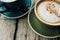 Coffee cappuccino in a green cup on a saucer. Two cups coffee on a wooden table