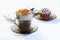 Coffee, cappuccino with whipped cream sprinkled with nuts, ground chocolate and cinnamon. Chocolate muffin in icing sugar.