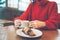 Coffee cappuccino in women`s hands on the table, girl in cozy red sweater