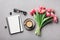 Coffee, clean notebook, eyeglasses and beautiful tulip flower on stone table top view in flat lay style. Woman working desk.