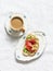 Coffee with cream and avocado, smoked salmon, grilled bread sandwich - delicious breakfast on a light background, top view