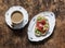 Coffee with cream and avocado, smoked salmon, grilled bread sandwich - delicious breakfast on a wooden background, top view