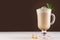 Coffee with cream, fresh mint, chocolate powder and cookies in irish coffee glass on dark brown and white wooden table, copy space