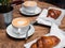 Coffee and croissant for breakfast. Cafe culture. Croissants with two small cups cappuccino with picture, top view