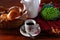 Coffee cup and buns basket with teapot and dried flowers on the fabric.