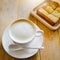 Coffee cup and butter toast on wooden table with warm sunlight morning soft focus at cream bubbles