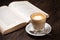 Coffee cup cappuccino hot latte or coffee with milk in a glass cup, open book