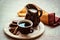 Coffee cup with cinnamon sticks, chocolate, milk on wooden plate on brown background