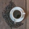 Coffee cup and coffee beans on old wooden desk background